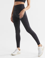 Person wearing black leggings and white sneakers on a white background