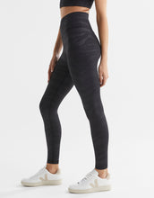 Person wearing black leggings and white sneakers on a light gray background