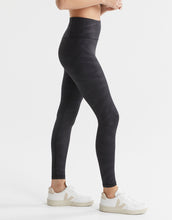 Person wearing black leggings and white sneakers on a white background