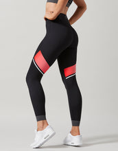 Black leggings with red accents worn by a person on a light gray background