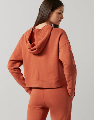 A woman wearing a copper hooded sweater and sweatpants.