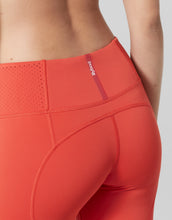Close-up of red athletic leggings with a brand logo on a neutral background
