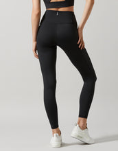A woman wearing a pair of high-waisted, full-length leggings in smoke black color, featuring breathable mesh panels and two pockets at the hip.