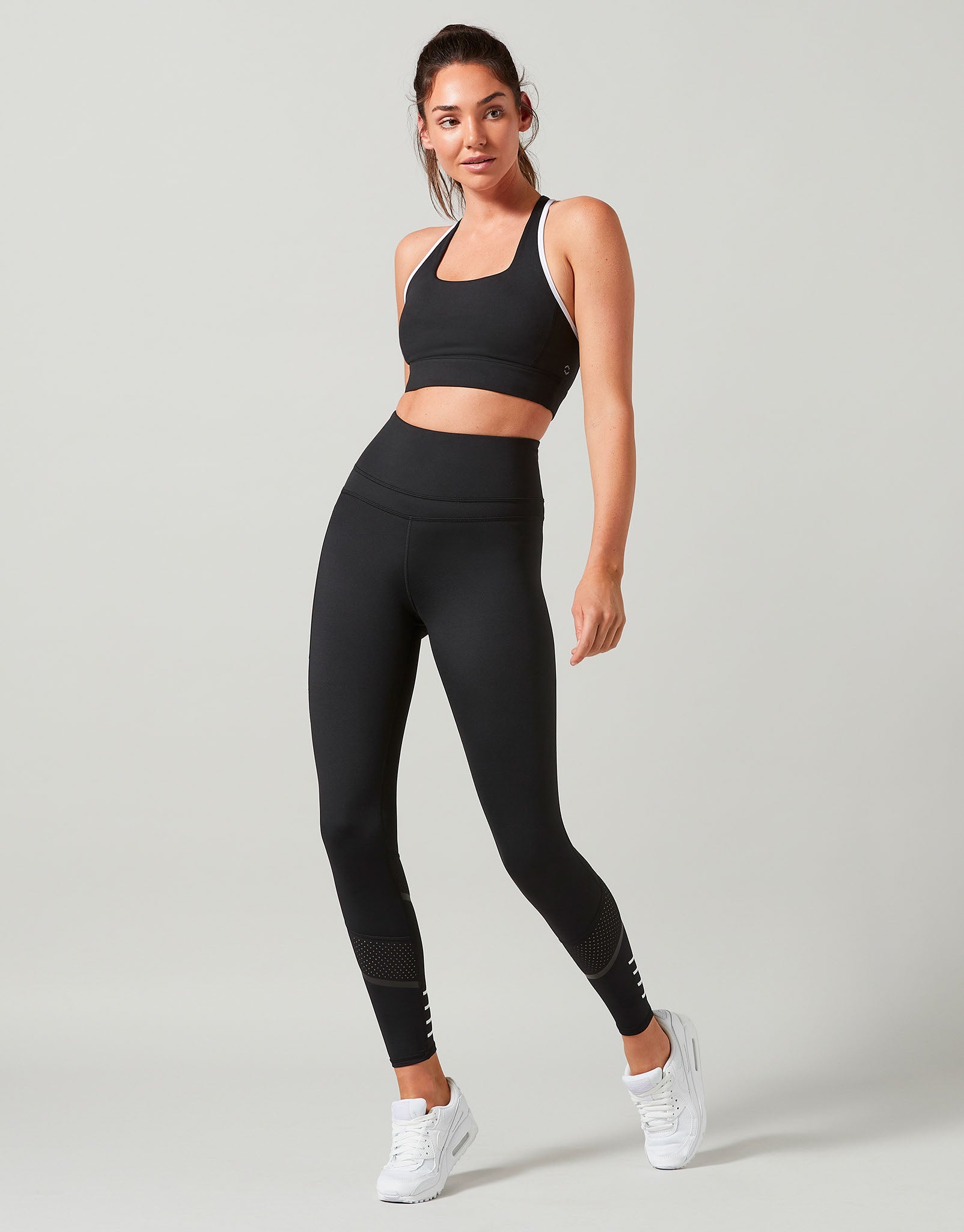 Woman wearing a black athletic outfit on a light gray background