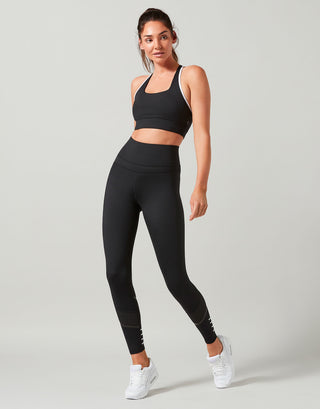 Woman wearing a black athletic outfit on a light gray background