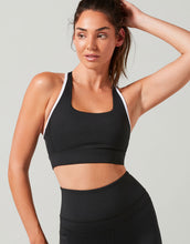 Woman wearing a black sports bra and leggings against a gray background