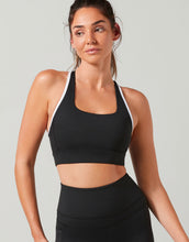 Woman wearing a black sports bra and leggings on a gray background