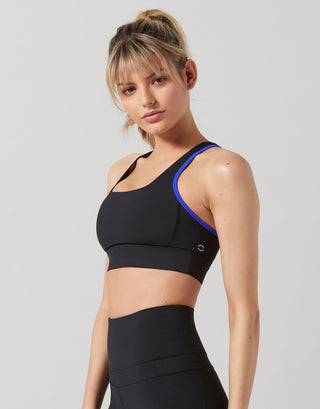 A woman wearing a black sports bra and black leggings.