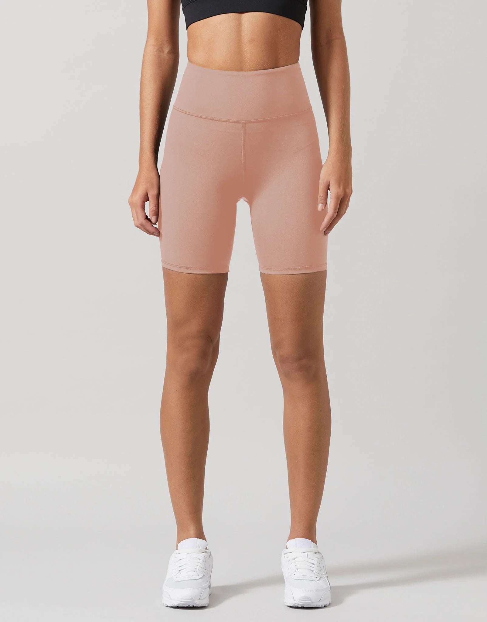 A model wearing beige workout shorts and a black top.
