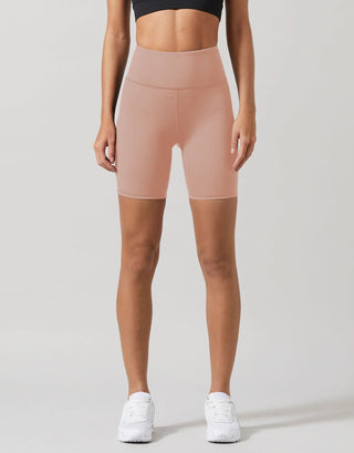 A model wearing beige workout shorts and a black top.