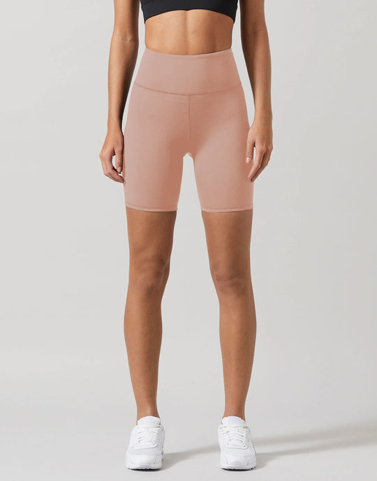 A model wearing beige workout shorts and a black top.