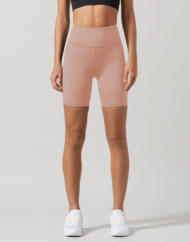 A model wearing beige workout shorts and a black top.