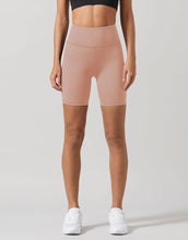 A model wearing beige workout shorts and a black top.