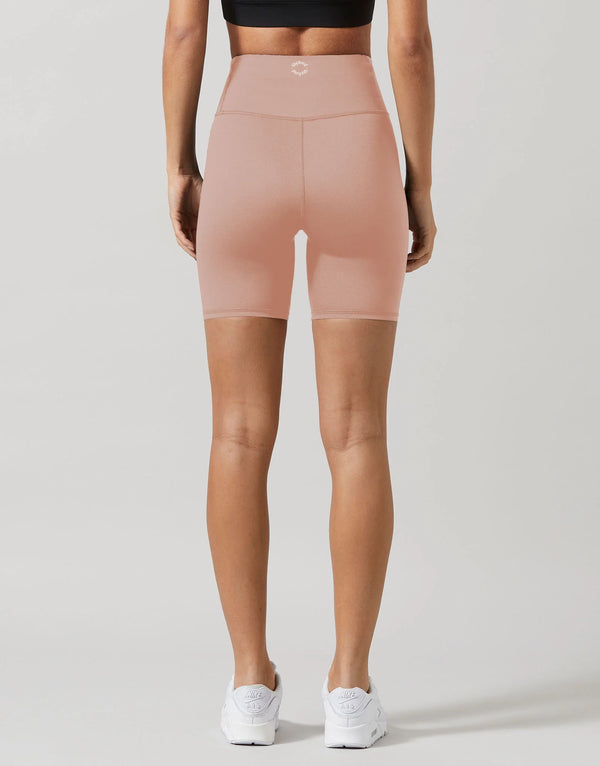 A woman wearing beige activewear shorts and white runners.