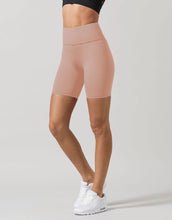 Person wearing beige high-waisted leggings on a plain background