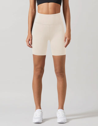 Person wearing beige high-waisted shorts on a plain background