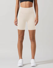 Person wearing beige high-waisted shorts on a plain background