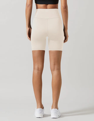 Person wearing beige high-waisted shorts on a plain background