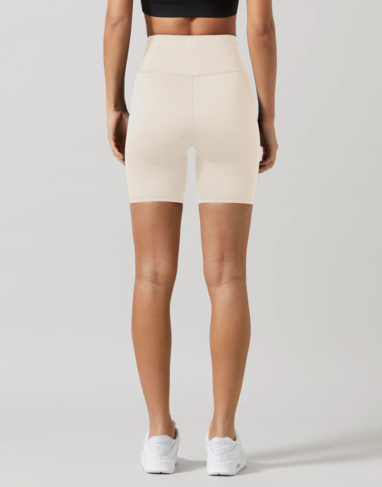 Person wearing beige high-waisted shorts on a plain background
