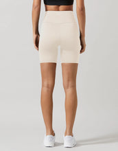 Person wearing beige high-waisted shorts on a plain background