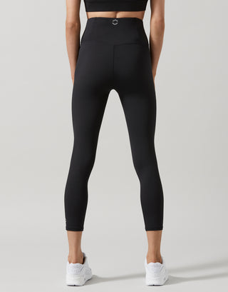 A woman wearing black 7/8 length leggings and white runners.