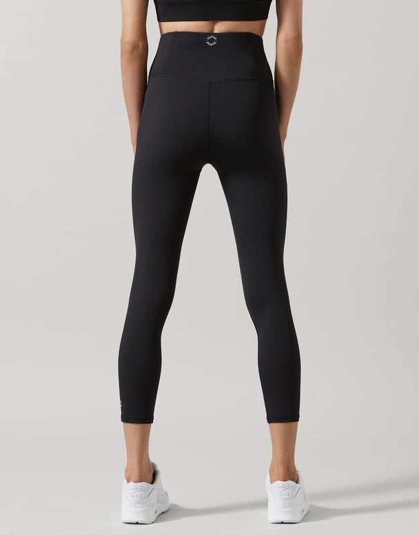 A woman wearing black 7/8 length leggings and white runners.