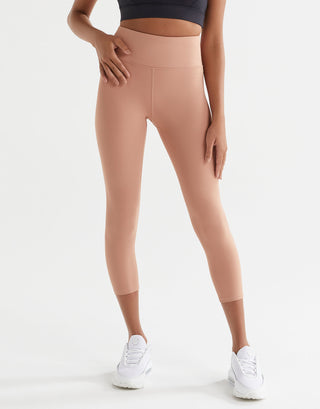 Person wearing beige leggings and white sneakers on a light gray background