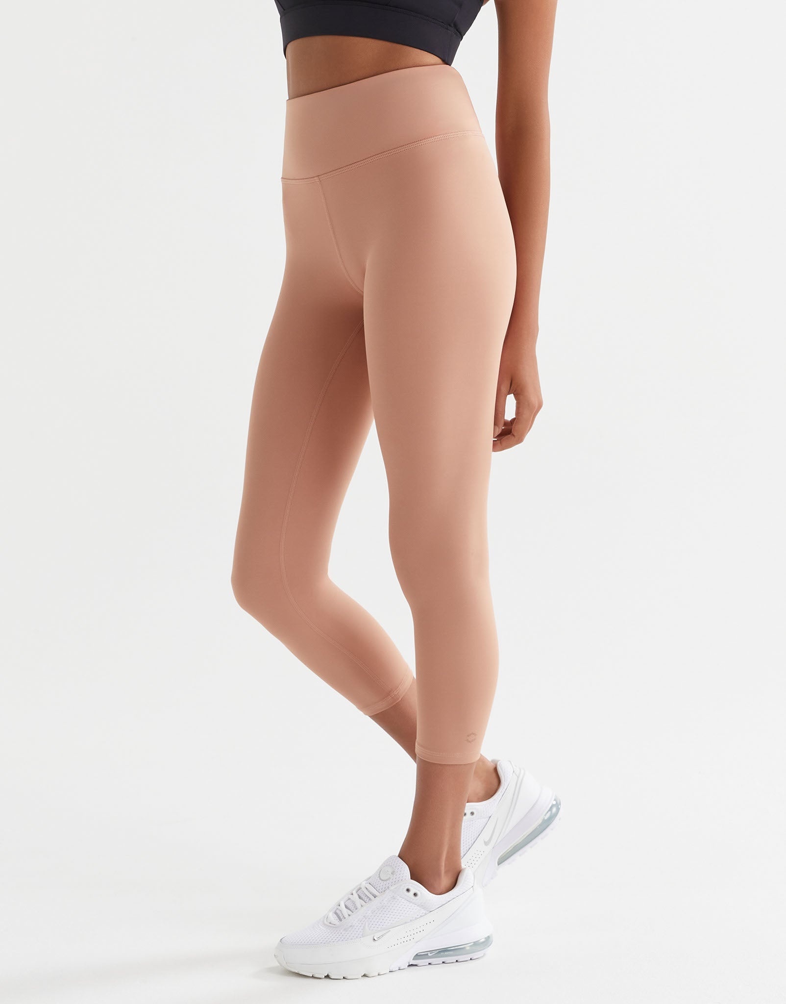 Person wearing beige leggings and white sneakers on a light gray background