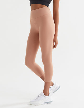 Person wearing beige leggings and white sneakers on a light gray background