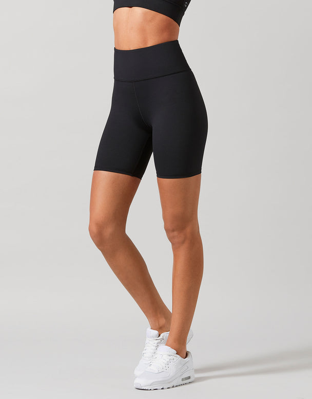 A pair of high-waisted black bike shorts with a 6-inch inseam, designed for women, worn by a model.