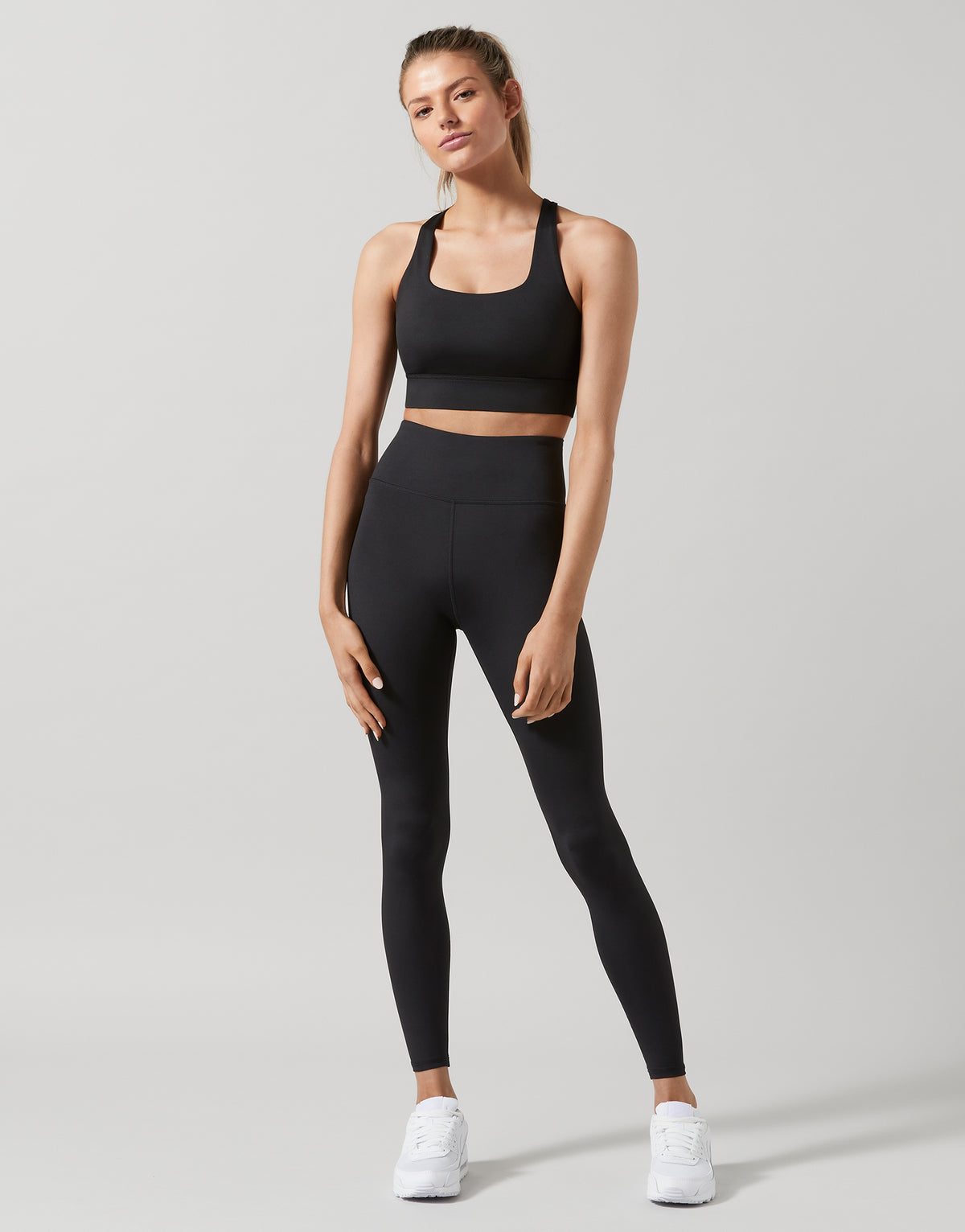 A woman wearing black high-waisted full-length leggings, standing.