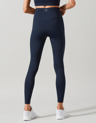 A woman wearing navy blue leggings and white sneakers.