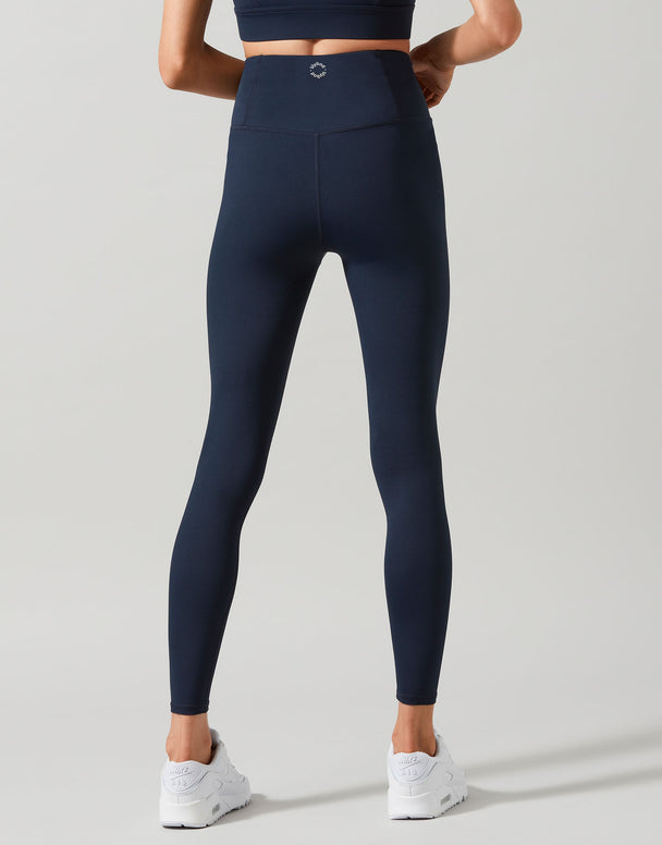 A woman wearing navy blue leggings and white sneakers.