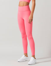Person wearing bright pink leggings and white sneakers on a light gray background