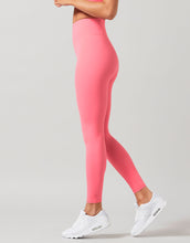 Person wearing pink leggings and white sneakers on a gray background