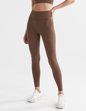A pair of full-length brown leggings with a high-waisted fit, paired with a matching sports bra and white sneakers.