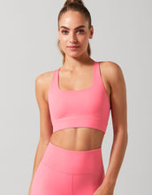 Woman wearing a pink sports bra and leggings against a gray background