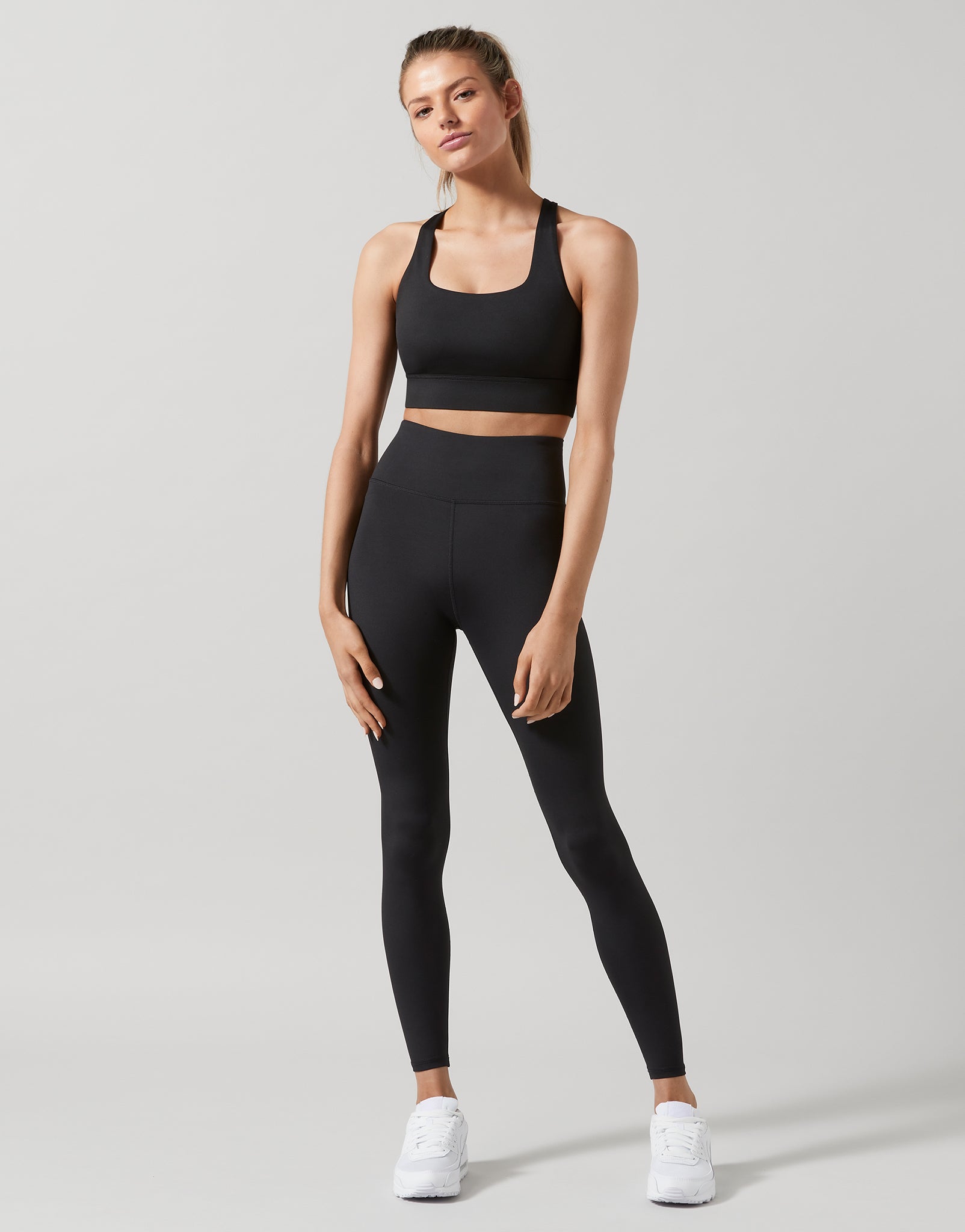 Woman wearing a black athletic outfit on a light gray background