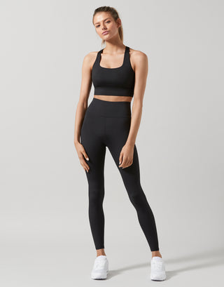 Woman wearing a black athletic outfit on a light gray background