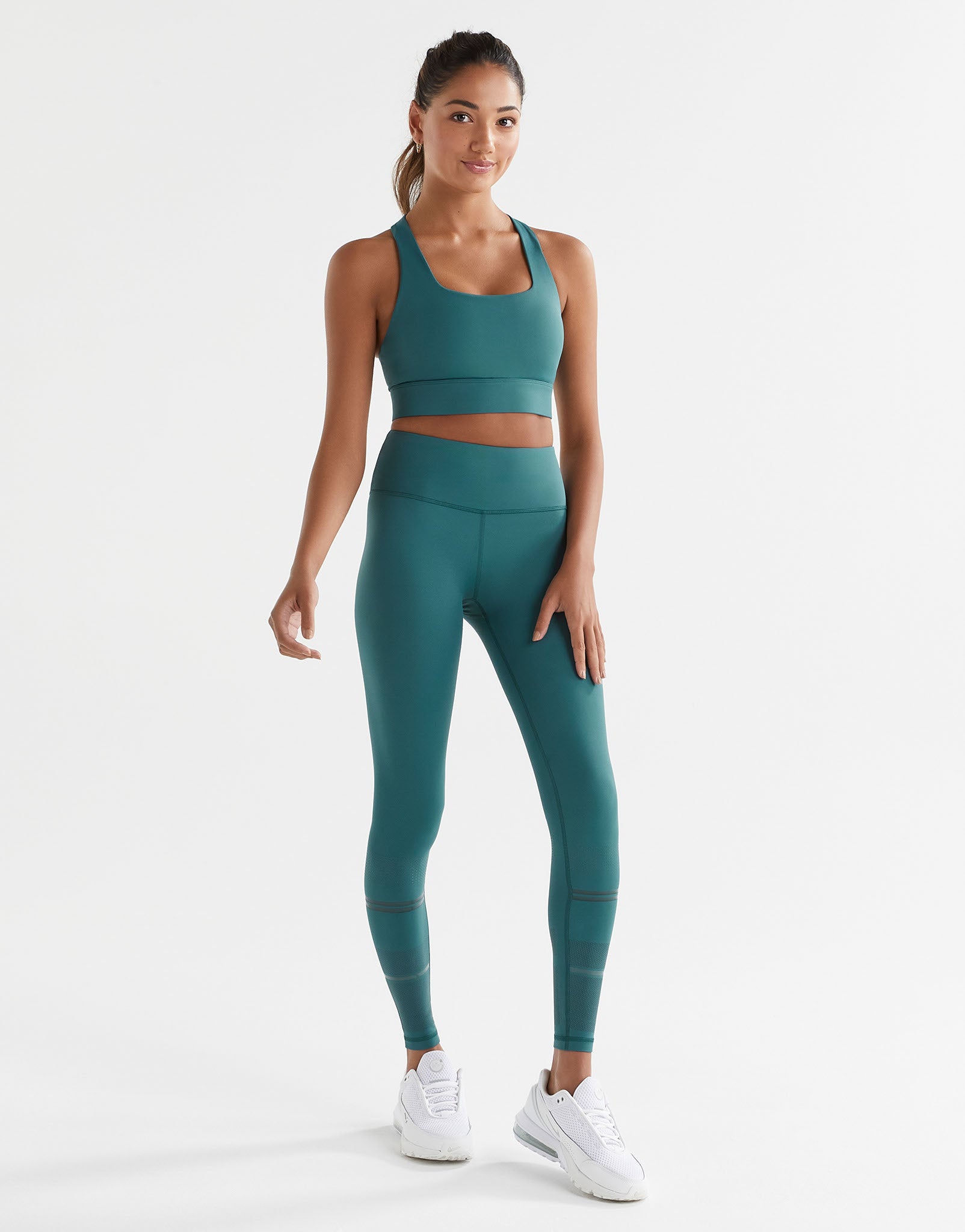 Woman wearing a teal athletic outfit on a white background