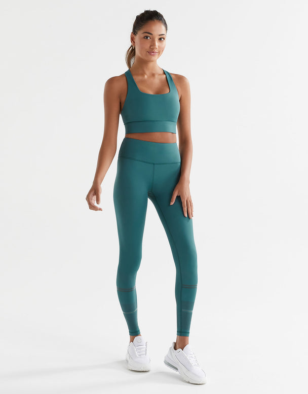 Woman wearing a teal athletic outfit on a white background