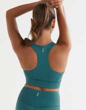 Person wearing a teal sports bra and leggings on a light gray background