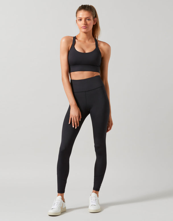 A model wearing full-length black Lilybod leggings that are high-waisted and made of recycled compression fabric.