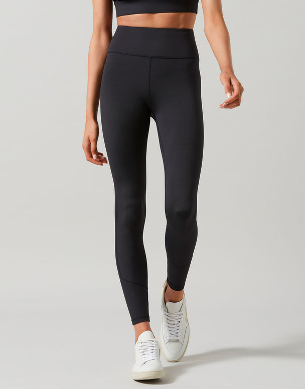A model wearing full-length black leggings that are high-waisted and made of recycled compression fabric.