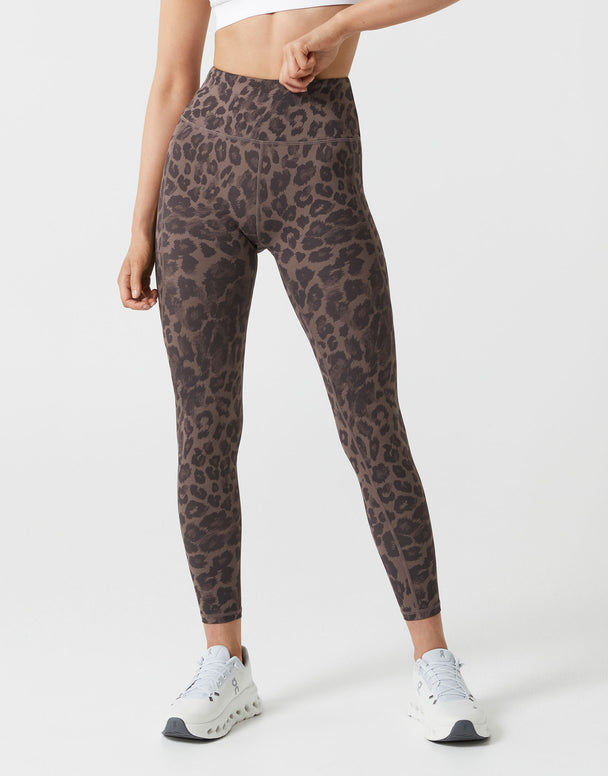 Person wearing leopard print leggings on a white background