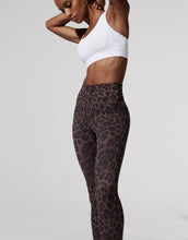 Person wearing a white sports bra and leopard print leggings on a light gray background