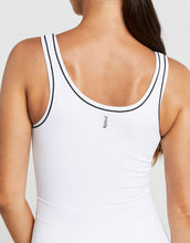 White tank top with black trim worn by a person on a light gray background