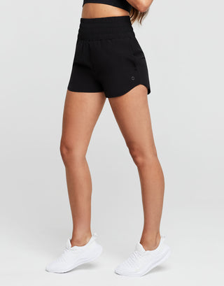 Person wearing black shorts and white sneakers on a plain background