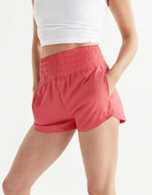 Person wearing pink shorts and a white top on a white background