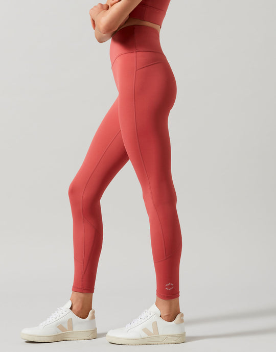 Person wearing red leggings and white sneakers on a light gray background